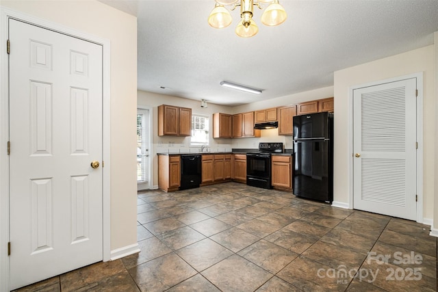 kitchen with baseboards, black appliances, under cabinet range hood, dark countertops, and a chandelier