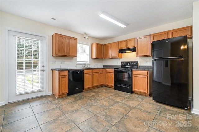 kitchen featuring under cabinet range hood, visible vents, black appliances, and dark countertops