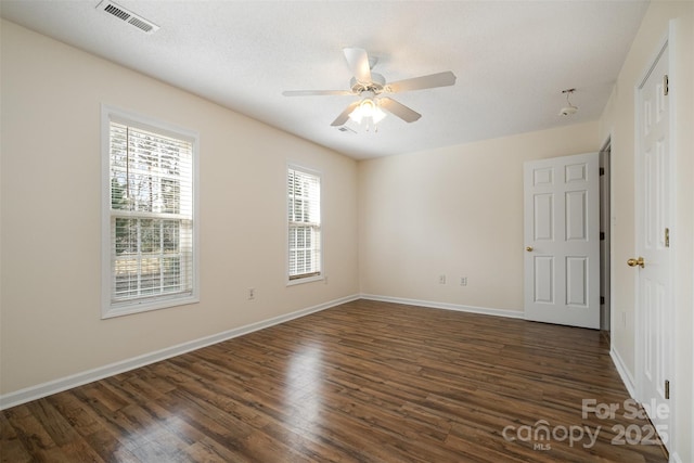 spare room with dark wood finished floors, visible vents, and ceiling fan