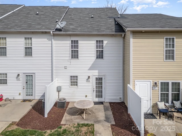 rear view of property featuring a patio area, a shingled roof, and fence