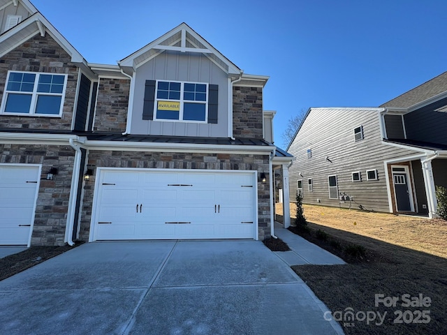 view of front facade featuring an attached garage, stone siding, board and batten siding, and concrete driveway