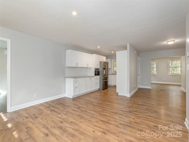 unfurnished living room featuring light wood-style floors, baseboards, and recessed lighting