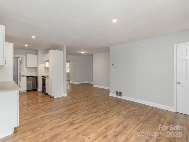 unfurnished living room featuring visible vents, recessed lighting, light wood-style flooring, and baseboards