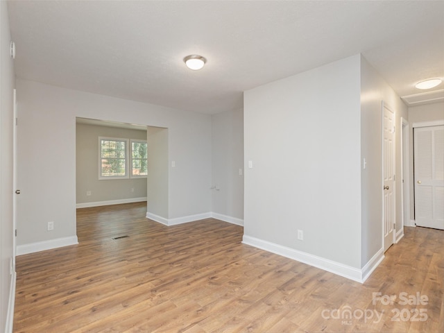 spare room featuring light wood finished floors and baseboards