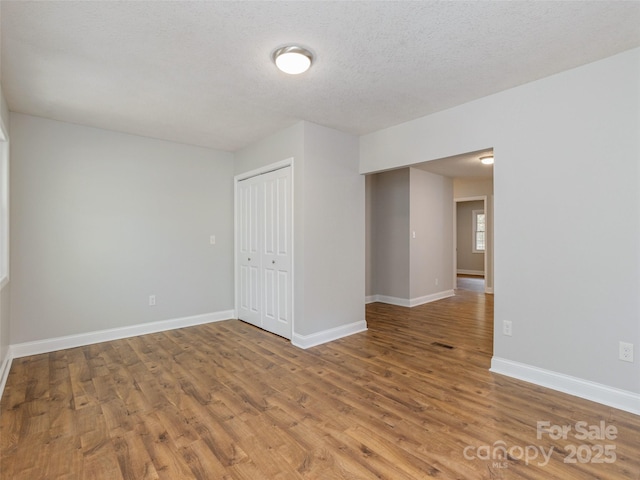 empty room with visible vents, a textured ceiling, baseboards, and wood finished floors