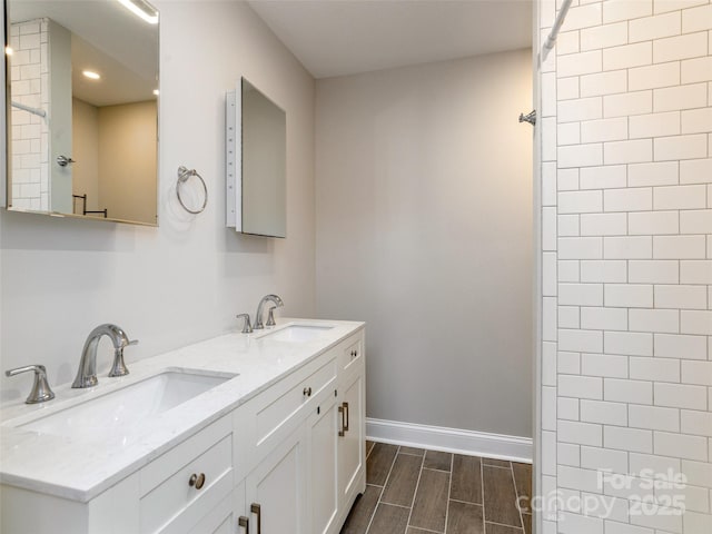 bathroom featuring double vanity, baseboards, a sink, and wood finish floors