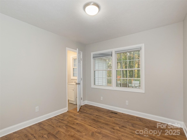 spare room featuring visible vents, baseboards, and wood finished floors