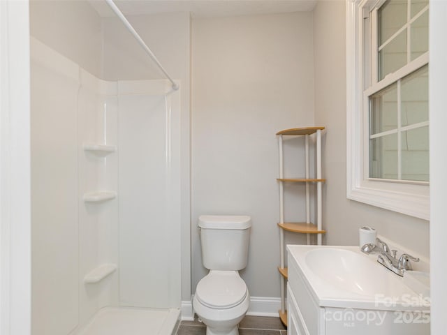 bathroom featuring a shower, baseboards, vanity, and toilet