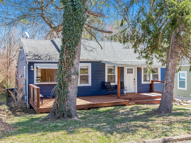 view of front of home featuring roof with shingles and a front yard