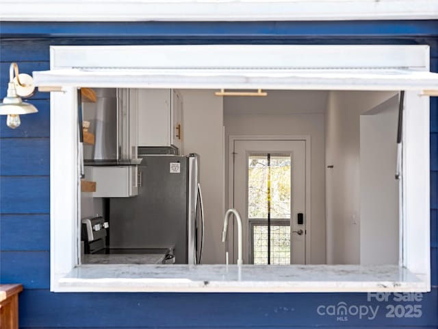 kitchen featuring a sink, light stone counters, exhaust hood, and stainless steel appliances