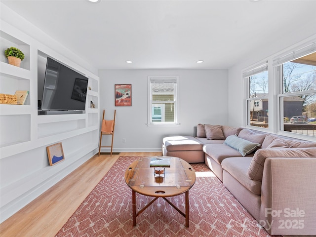 living room with built in shelves, baseboards, plenty of natural light, and wood finished floors