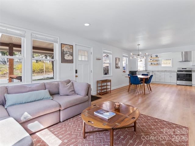 living room with recessed lighting, a notable chandelier, baseboards, and light wood-style floors