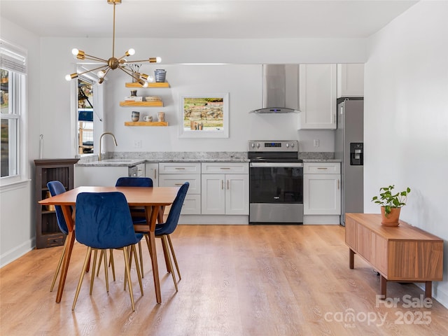 kitchen featuring an inviting chandelier, a sink, stainless steel appliances, white cabinetry, and wall chimney exhaust hood