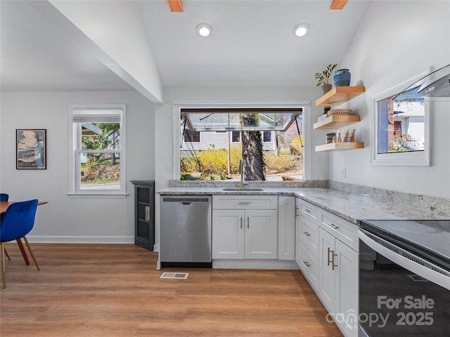 kitchen featuring a sink, plenty of natural light, stainless steel dishwasher, light wood finished floors, and light stone countertops