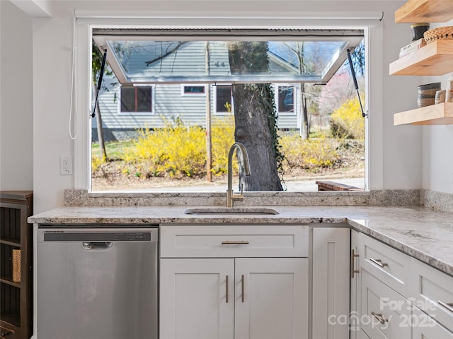 kitchen with light stone countertops, open shelves, a sink, white cabinets, and stainless steel dishwasher