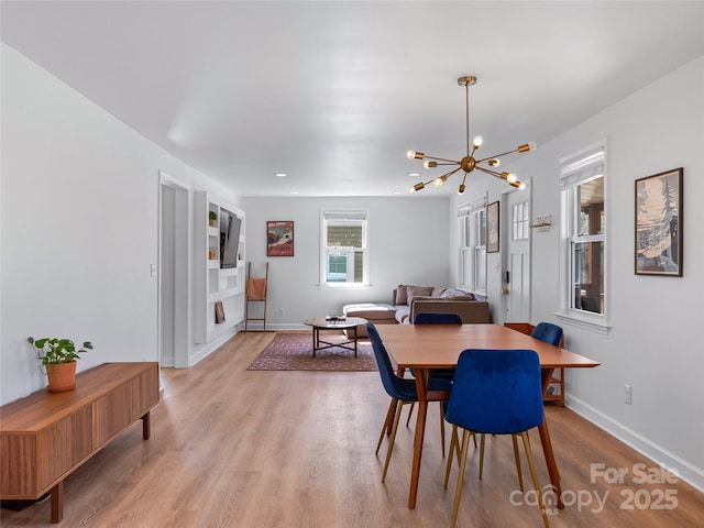 dining space featuring light wood-type flooring, baseboards, and a notable chandelier