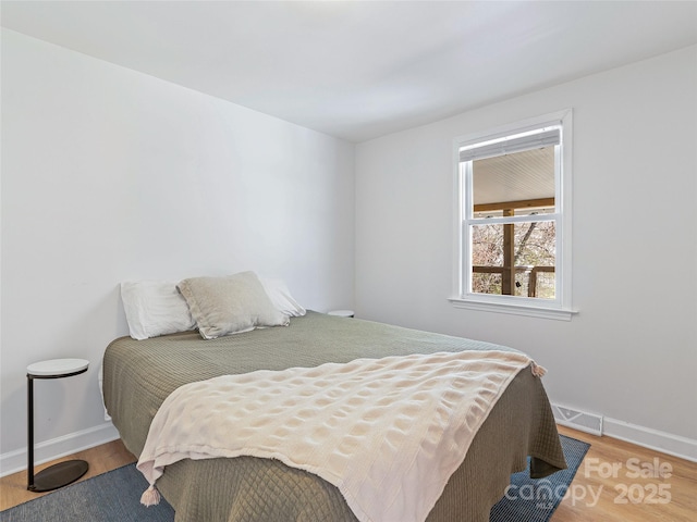 bedroom with visible vents, baseboards, and wood finished floors