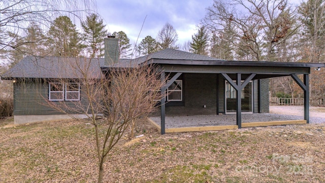 back of property featuring brick siding and a chimney