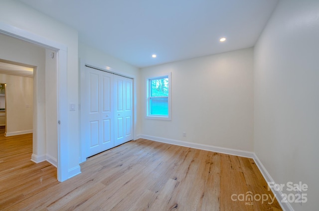 unfurnished bedroom featuring baseboards, a closet, recessed lighting, and light wood-style floors