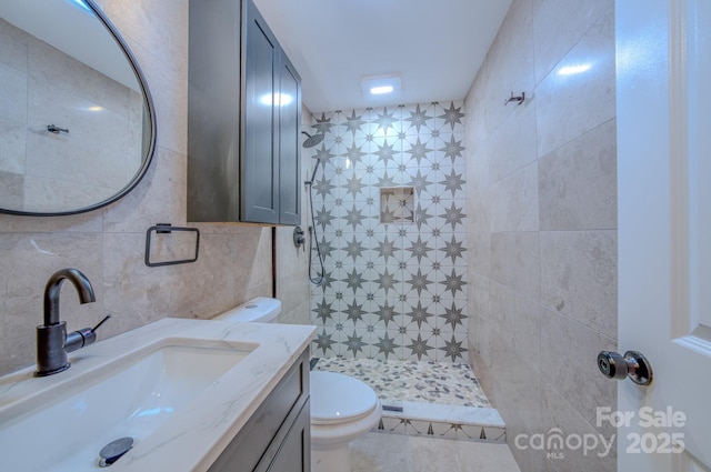 full bath with tasteful backsplash, tiled shower, toilet, vanity, and tile walls