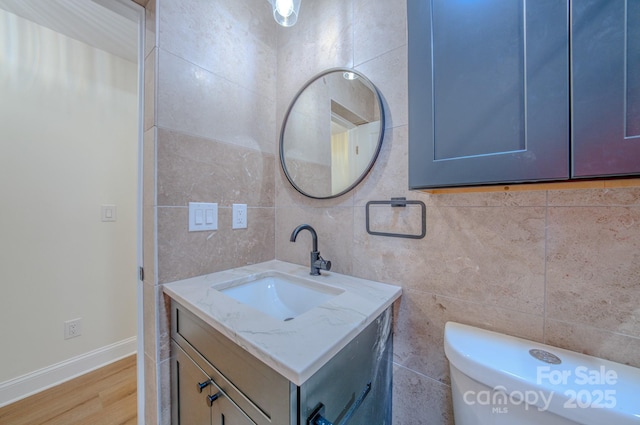 bathroom featuring tile walls, wood finished floors, vanity, and baseboards