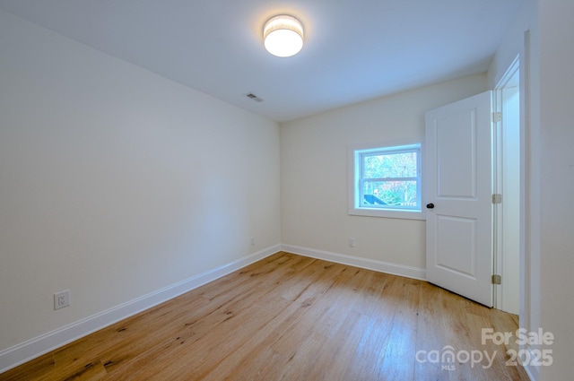 empty room with light wood-style floors, visible vents, and baseboards