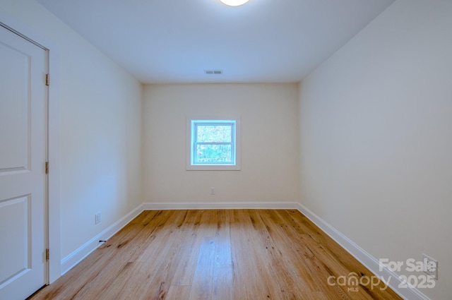 unfurnished room featuring visible vents, baseboards, and wood finished floors