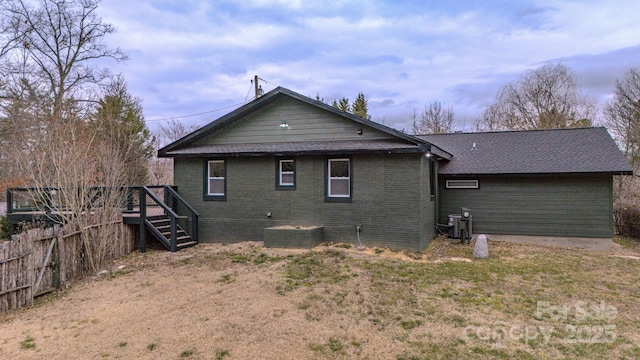 rear view of house with fence, stairway, and brick siding