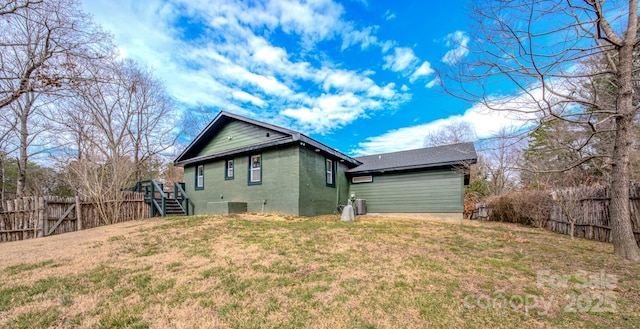 rear view of property with a fenced backyard, stairs, a lawn, and brick siding