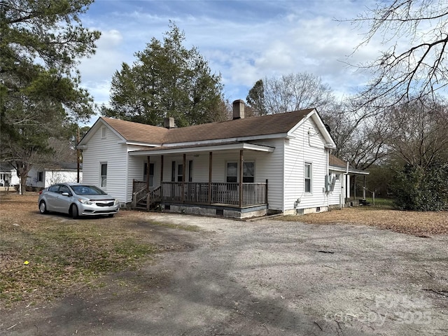 ranch-style home featuring a porch, roof with shingles, driveway, and a chimney