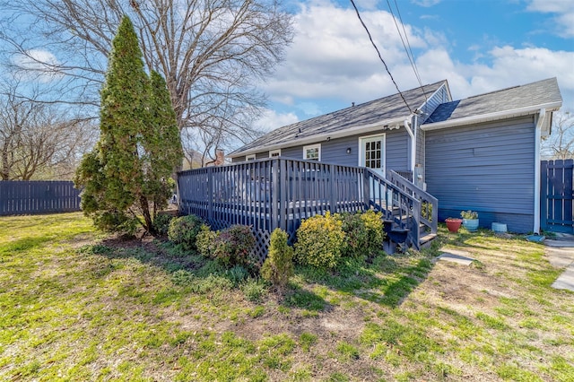 rear view of property featuring a deck, a lawn, and fence