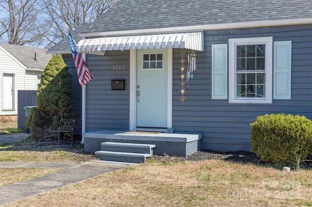 view of exterior entry with a shingled roof