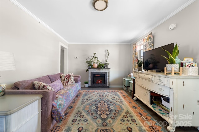 living area with a lit fireplace, baseboards, crown molding, and wood finished floors