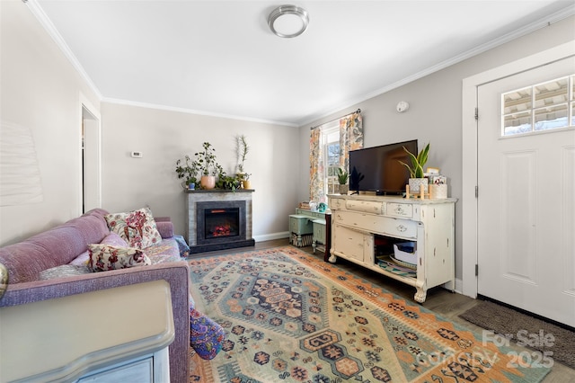 living area with ornamental molding, a lit fireplace, baseboards, and wood finished floors