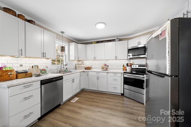 kitchen featuring light wood finished floors, tasteful backsplash, visible vents, stainless steel appliances, and a sink