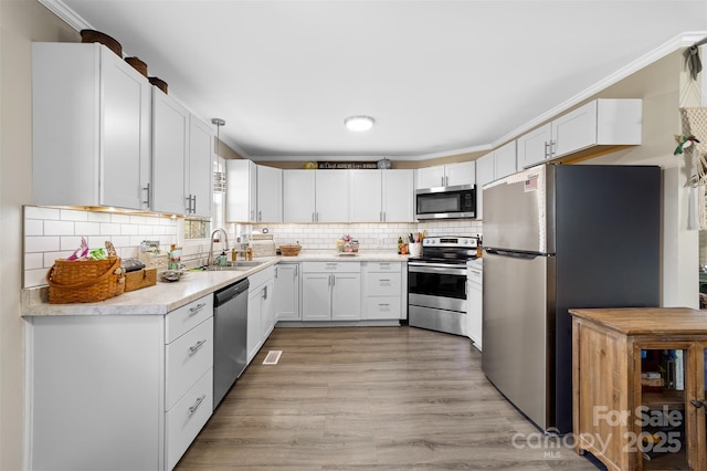 kitchen featuring ornamental molding, appliances with stainless steel finishes, backsplash, and a sink