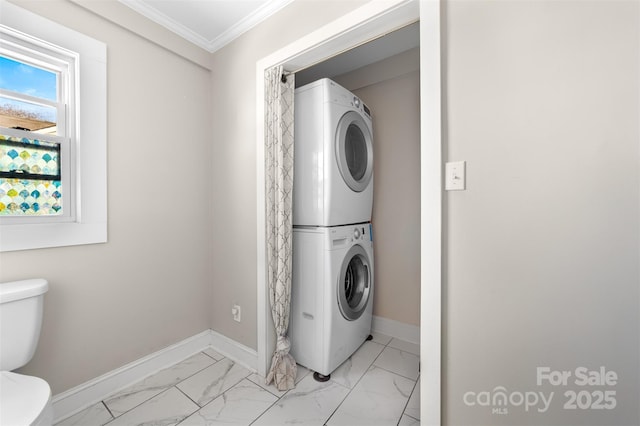 laundry area with marble finish floor, ornamental molding, stacked washing maching and dryer, laundry area, and baseboards