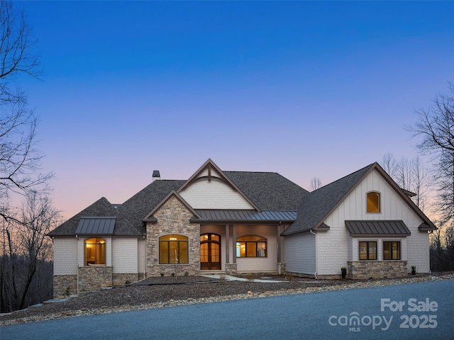 view of front of house with a standing seam roof, metal roof, stone siding, and a shingled roof