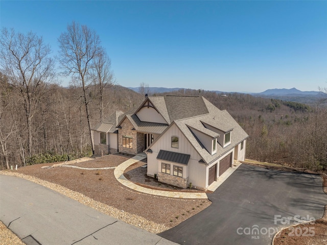 view of front of house featuring driveway, a shingled roof, a garage, board and batten siding, and a mountain view