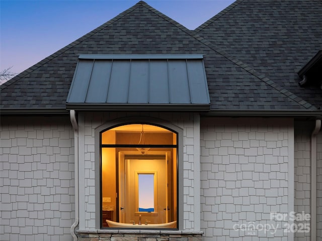 exterior entry at dusk with a shingled roof