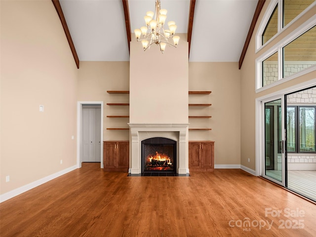 unfurnished living room with a chandelier, a fireplace with flush hearth, baseboards, and wood finished floors