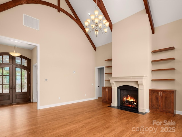 unfurnished living room featuring visible vents, baseboards, wood finished floors, and french doors