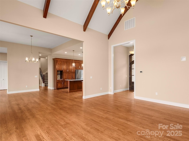 unfurnished living room with stairway, visible vents, light wood finished floors, beam ceiling, and a notable chandelier