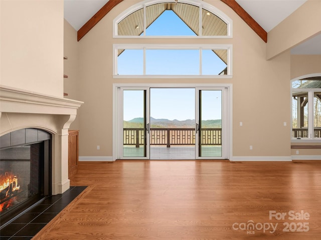 unfurnished living room featuring a wealth of natural light, a mountain view, wood finished floors, and a tile fireplace