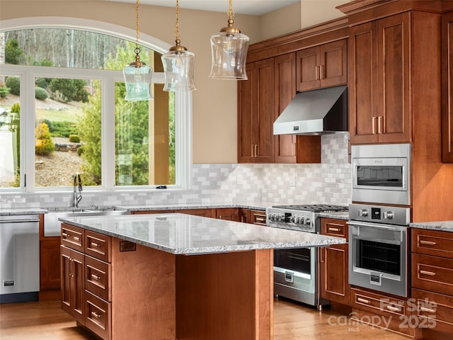 kitchen with light wood-type flooring, a sink, a kitchen island, stainless steel appliances, and extractor fan