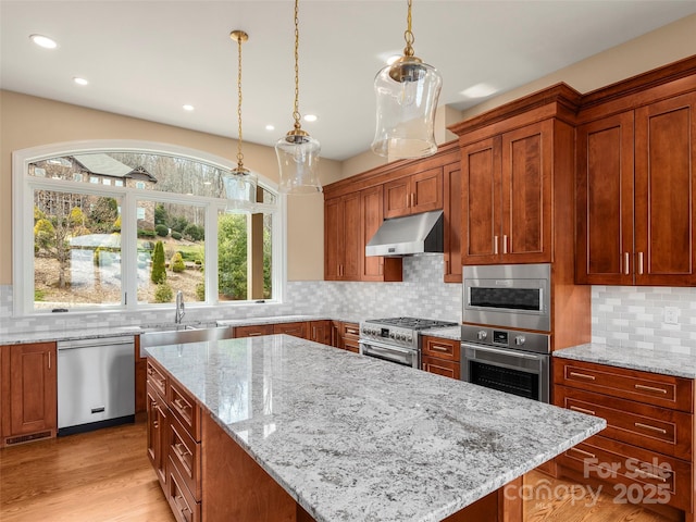 kitchen with under cabinet range hood, a sink, a center island, stainless steel appliances, and light stone countertops