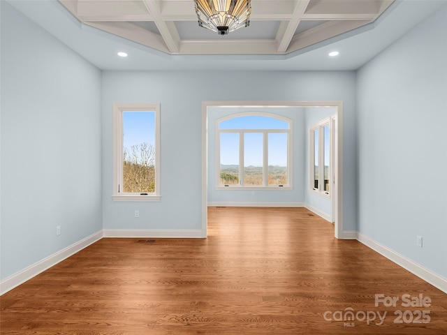 unfurnished room with coffered ceiling, baseboards, and wood finished floors