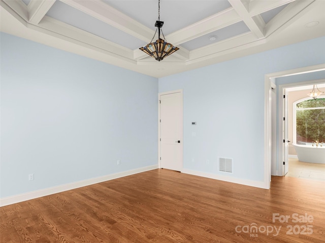 empty room with visible vents, coffered ceiling, baseboards, and wood finished floors