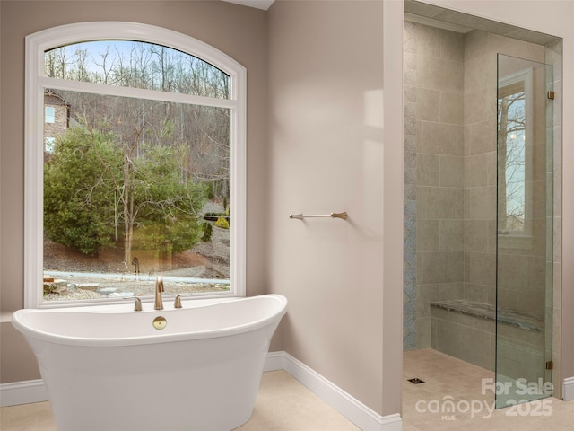 bathroom featuring a freestanding tub, baseboards, and tiled shower