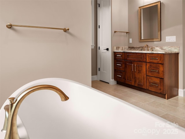 full bath with baseboards, a soaking tub, vanity, and tile patterned flooring